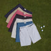 Reyn Spooner Aloha 'Aina 4 Way Stretch Shorts in Black, Grey, Nantucket Red, Khaki, Stone and Medium Blue. on green turf with golf balls and tees.