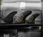 Futures Alpha Vector 3/2 size Large thruster fin set made of black recycled carbon with gold accents  installed in a surfboard