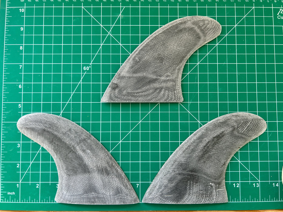 Three black opaque thruster used glass on fins displayed on a green grid