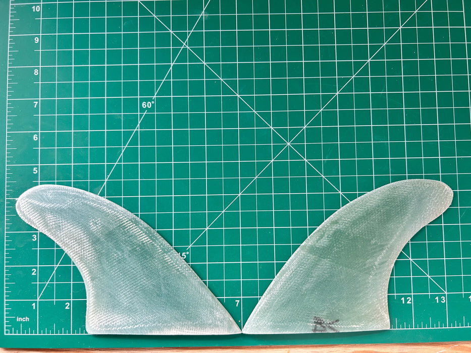 4 3/8" Teal translucent used fiberglass glass on twin fins on a green grid