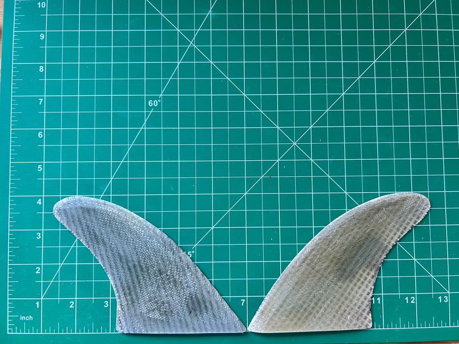 4" used translucent fiberglass with carbon weave glass on twin fins, side bites or half a quad set on a green grid 