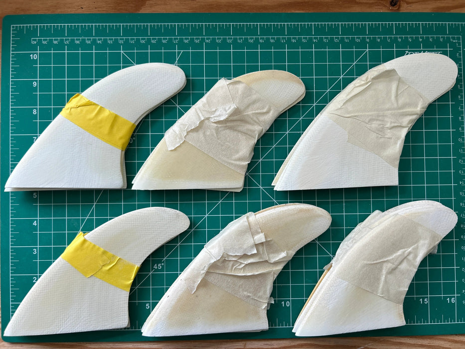 Many sets of white opaque thruster used glass on fins stacked one on top of each other displayed on a green grid