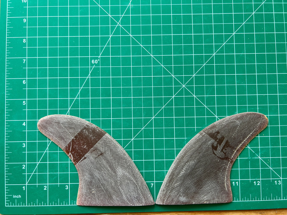 Black opaque 4 1/4" used fiberglass glass on twin fins, side bites or half a quad set on a green grid 