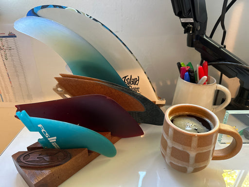 Small wood base to display different size surfing fins on a desk with coffee