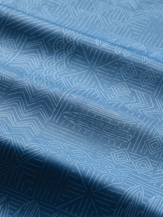 Close-up of a blue quarter-zip pullover with a subtle white line Tapa pattern of waves surfboards and and other Hawaiian elements; Reyn Spooner label inside the collar.