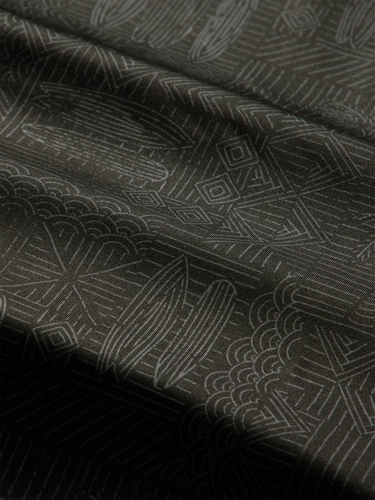 Close-up of a charcoal colored quarter-zip pullover with a subtle white line Tapa pattern of waves surfboards and and other Hawaiian elements; Reyn Spooner label inside the collar.