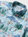 Close up of a light blue collared buttoned up Aloha shirt featuring Looney Tunes cartoon characters Bugs Bunny, Sylvester and many others.