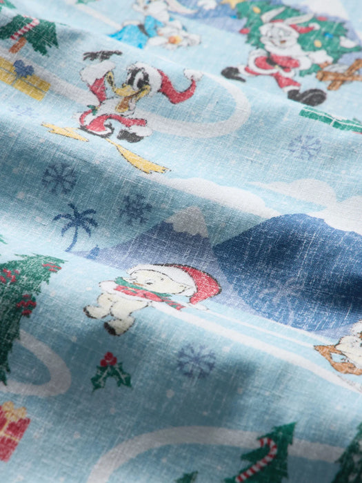 Super zoom in on a light blue fabric with Looney Tunes cartoon characters Bugs Bunny, Daffy Duck and others with a candy cane on a Christmas trees. 