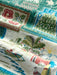 Super zoom in on a scene of a beached sea canoe with presents with an ama in front of a Hale with a Christmas decorated palm tree in green theme.