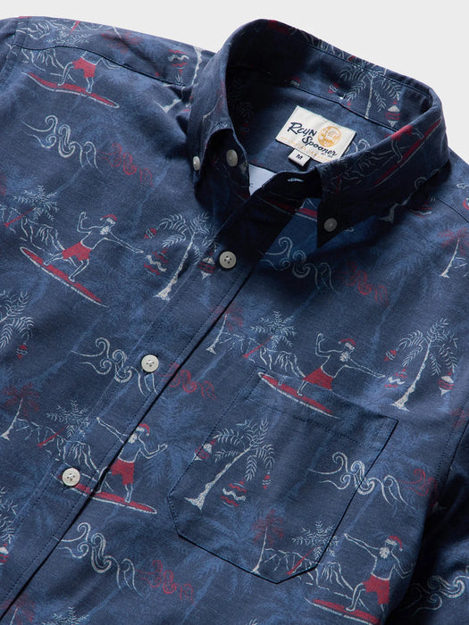 Close up of Surfin' Santa Performance Button Front Collared Short Sleeve Navy colored Aloha Shirt depicts Santa Surfing Waikiki with Diamondhead in the background.