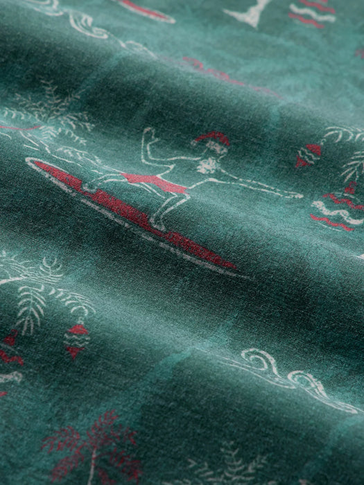 A close-up of pine colored fabric with a printed pattern of white line-art of Santa surfing with Diamondhead in the background.