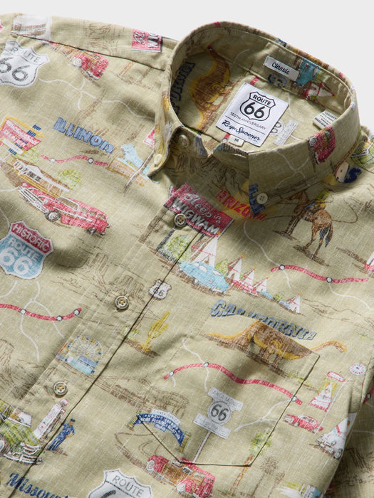Close up of a button-up collared classic shirt with an all-over khaki fabric map print featuring Route 66 motifs, illustrated landmarks, and small colorful details.