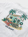 Close-up of a white t-shirt featuring a graphic of a festive Hawaiian beach scene with Santa Claus, a surf hut, palm trees, and the text 'MELE KALIKIMAKA HAWAII' and 'REYN SPOONER'.
