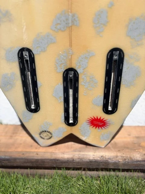 Close-up of the tail section of a short board surfboard with three of five Futures black fin boxes.